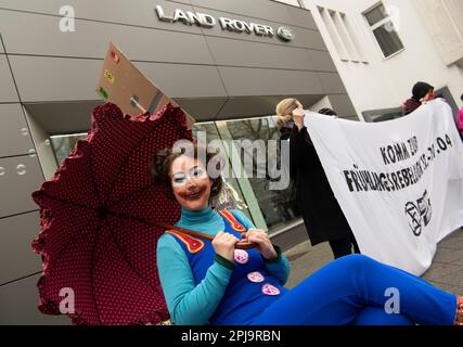 Berlin, Germany. 01st Apr, 2023. An activist dressed as a clown from the group 'Extinction Rebellion' protests in front of the luxury sports car branch of Jaguar and Landrover on Kurfürstendamm for more decisive political action against the climate crisis. Credit: Paul Zinken/dpa/Alamy Live News Stock Photo