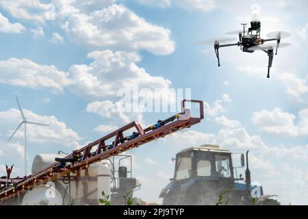 Machine for spraying pesticides and herbicides and drone sprayer in a field at work. Wind turbines on a horizon. Smart farming concept. Stock Photo