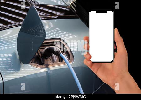 Hand with smartphone on a background of electric car . White screen, you can add your content here.. High quality photo Stock Photo