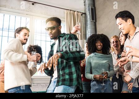 Multi ethnic young friends having home party together - Funny diverse people having fun dancing and singing in the living room during cool party - You Stock Photo