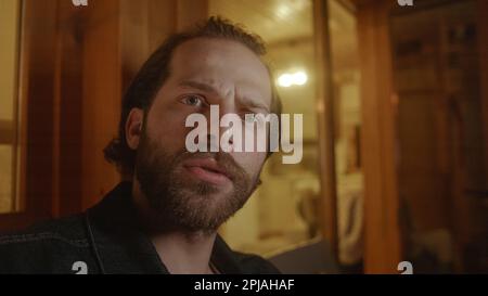 Serious Video Call on the Balcony of a Wooden House with Yellow Lights, Person Of View Shot Stock Photo