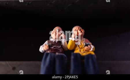 Toy of old woman and man sitting on wall with black background. Selective focus. Stock Photo