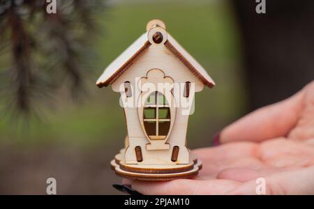 Girl holds a small wooden house outdoors Stock Photo