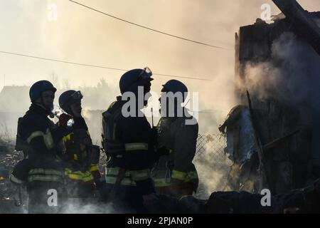 Zaporizhzhia, Ukraine. 31st Mar, 2023. Ukrainian State Emergency Service firefighters take a break following Russian shelling that hit a suburban area in Zaporizhzhia. On the night of March 31, the Russian occupying army shelled Zaporizhzhia with MLRS (Multiple Launch Rocket System). As the Ukrainian News Agency earlier reported, in addition, during the night, the aggressor country, the Russian Federation, launched 10 Shahed attack drones over Ukraine, 9 of which were destroyed by the air defense forces. Credit: SOPA Images Limited/Alamy Live News Stock Photo
