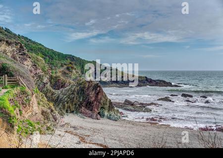 Small section of rural coastline by the more easterly beach at Talland Bay, Cornwall. The superb rock colours add to the natural beauty of the bay. Stock Photo