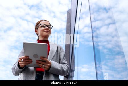Businesswoman with digital tablet next to office building. Stock Photo