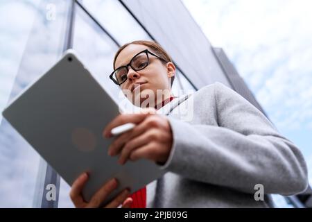 Confident woman wearing glasses working on digital tablet. Stock Photo