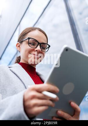 Female businessperson smiling while using het digital tablet and internet. Stock Photo