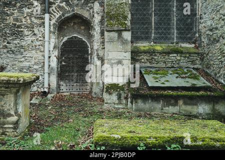 Detailed view of the entrance to a medieval church showing the crypt door. Damp moss is seen on surfaces due to being in near constant shadow. Stock Photo