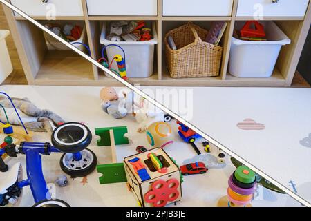 Children room littered with toys and a clean nursery, before and after cleaning. Mess due to toys scattered on the floor and things put away in a box, Stock Photo