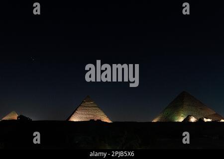 The Pyramids of Giza lit up with lights for the light and sound show at night in Egypt Stock Photo