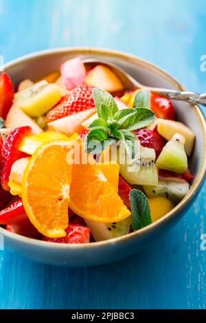Fresh fruit salad full of vitamins for summer with mint on blue background Stock Photo