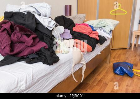 Messy teenager room. Untidy cluttered bed, dirty clothes. Compulsive Hoarding Syndrom Stock Photo