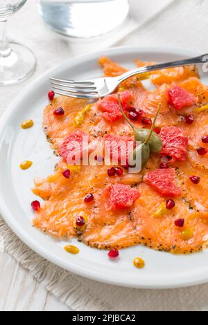 Salmon carpaccio with pink grapefruit and pomegranate on white plate Stock Photo
