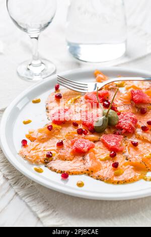Salmon carpaccio with pink grapefruit and pomegranate on white plate Stock Photo