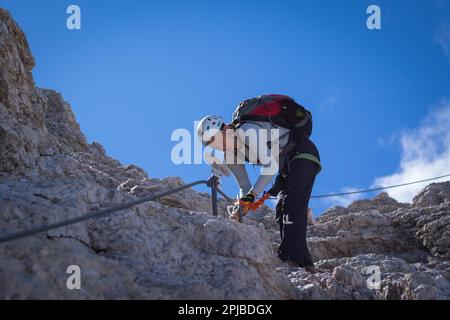 Tourist crossing the via ferrata trail with equipment in the dolomites. Dolomites, Italy, Dolomites, Italy, Europe Stock Photo