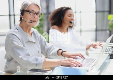 operator woman agent with headsets working in a call centre. Stock Photo