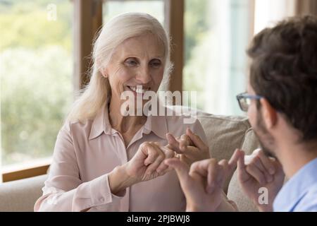 Old lady with hearing disability speaking sign language to man Stock Photo