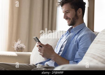 Happy handsome young man browsing Internet on mobile phone Stock Photo