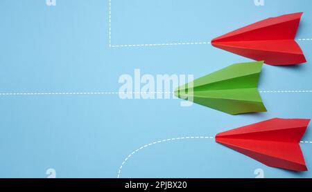 Three paper airplanes are moving forward, one turned sideways, representing the concept of individuality and non-standard thinking. Stock Photo
