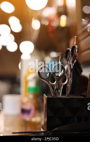 Professional hairdressing tools. Various steel scissors and combs, hairbrushes on wooden table on barbers workplace at barbershop salon. The concept o Stock Photo