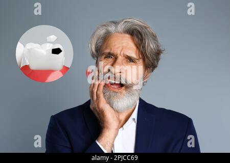 Mature man suffering from toothache on grey background Stock Photo