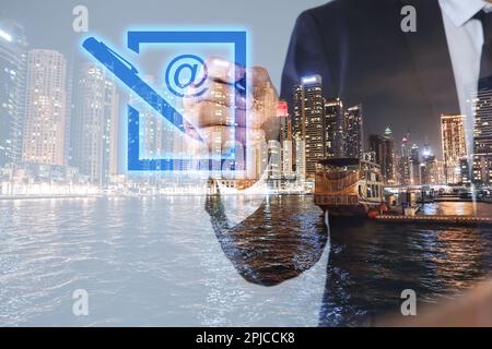 Electronic signature concept. Double exposure of businessman with pen near virtual screen and night cityscape