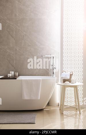 Modern white tub and table with toiletries in bathroom. Interior design ...