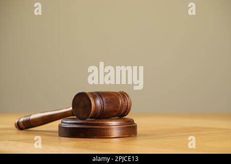 Wooden gavel on table against beige background. Space for text Stock Photo