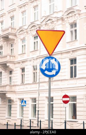 Post with Roundabout and Yield road signs on city street Stock Photo