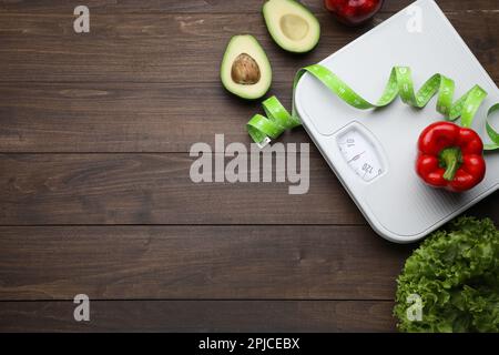 Flat lay composition with bathroom scale and measuring tape on wooden floor, space for text. Weight loss concept Stock Photo