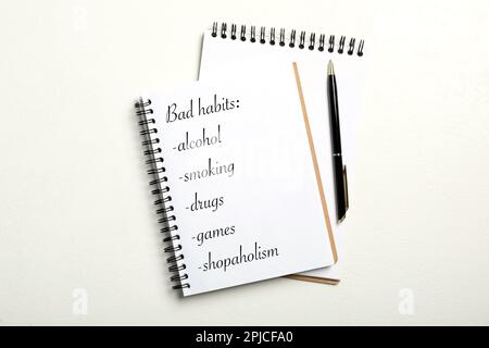 Notebook with list of bad habits on white table, flat lay Stock Photo