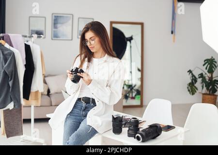 Female photographer in casual clothes is working indoors at daytime Stock Photo