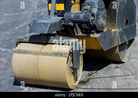 Construction worker in vibratory plate compactor process machine operator laying new asphalt Stock Photo