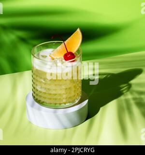 Whiskey sour trendy alcoholic cocktail with bourbon, lemon juice, egg white and ice in glass on bright green background, hard light, shadow pattern fr Stock Photo