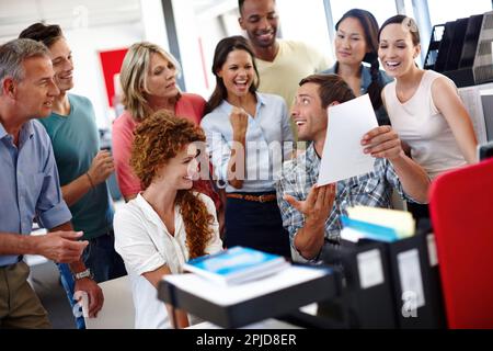 We reached our deadline. a young man showing something to his colleagues in the office. Stock Photo