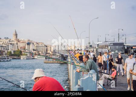 Istanbul, Turkey - August 13, 2022: Local citizens fishing at golden horn on Galata Bridge before sunset with Galata Tower in the background, Eminonu Stock Photo