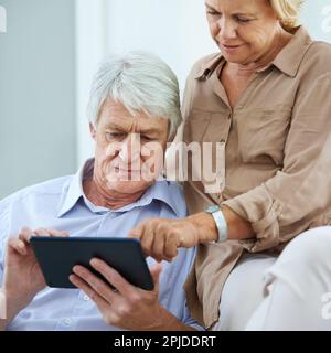 See, its all controlled by a touch. a happy elderly couple using a digital tablet together at home. Stock Photo