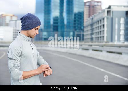 Racing against time. a young jogger checking the time while out for a run in the city. Stock Photo