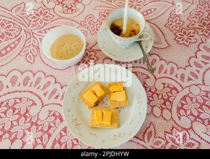Hot milk is poured in a cup with instant coffee placed in a floral edge saucer. A spoon in the saucer protrudes from the side of the cup. The cup and Stock Photo