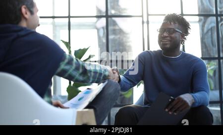 a black man with a folder in his hands shakes hands Stock Photo