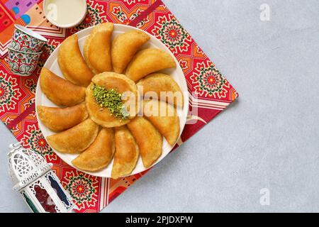 Arabian pancake Qatayef with qishta cream and pistachio . Traditional sweets with ramadan decor Stock Photo