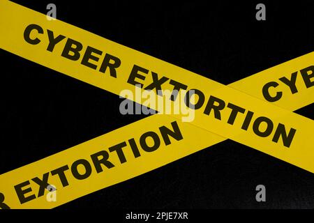 Cyber extortion caution and warning concept. Yellow barricade tape with word in dark black background. Stock Photo