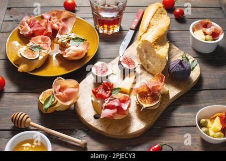 Appetizers board with traditional spanish tapas set. Italian antipasti bruschetta with prosciutto, cream cheese and fig. Stock Photo