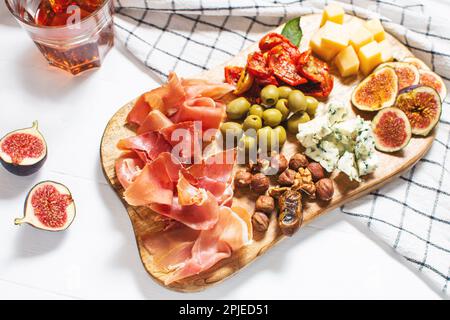 Antipasto platter with ham, prosciutto, blue cheese, dried tomatoes, figs and olives on a wooden bord. Stock Photo