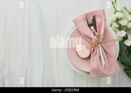 Easter brunch table setting. Spring Easter holiday concept with white, pink plate and napkin with decorative symbols holiday rabbit, eggs and bouquet Stock Photo