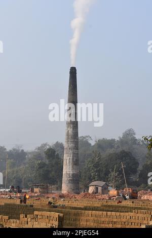 A chimney of a brick factory in Tripura causing pollution with blue sky . Stock Photo