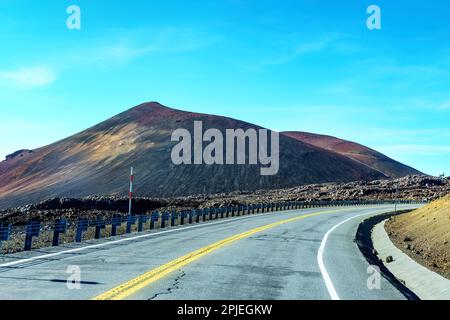 Mauna Kea Road winding through the rocky landscape and rugged terrain of Hawaii. Stock Photo