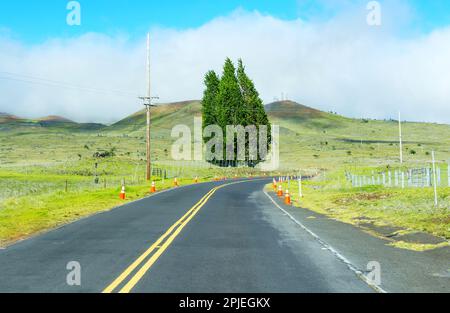 Natural beauty of Hawaii's Mauna Kea mountain range, with a winding road leading through the lush green hills that surround it. Stock Photo