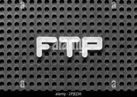 White alphabet letter in word FTP (Abbreviation of File Transfer Protocol) on black pegboard background Stock Photo